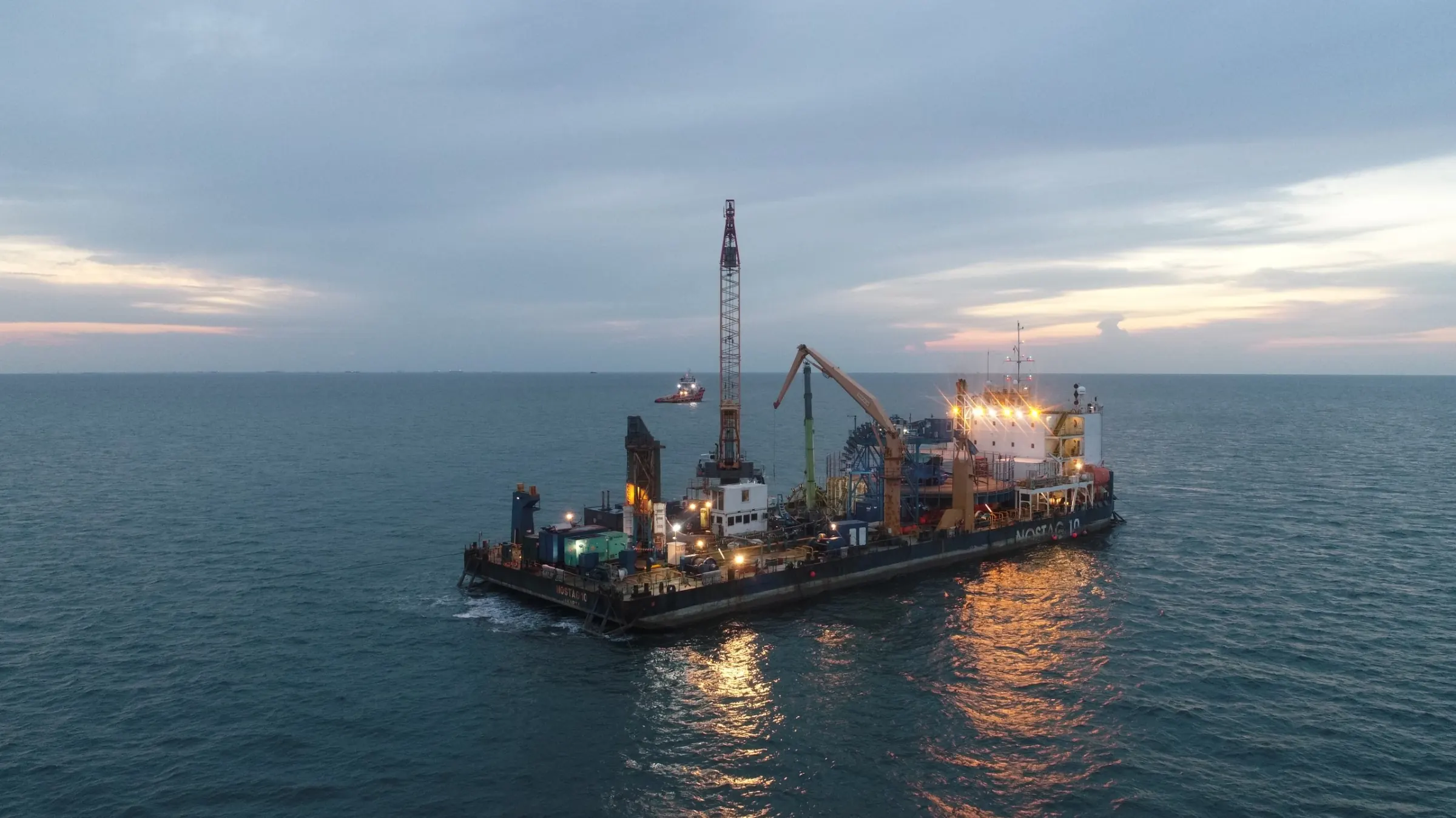 Cable-laying barge working at sea at dusk